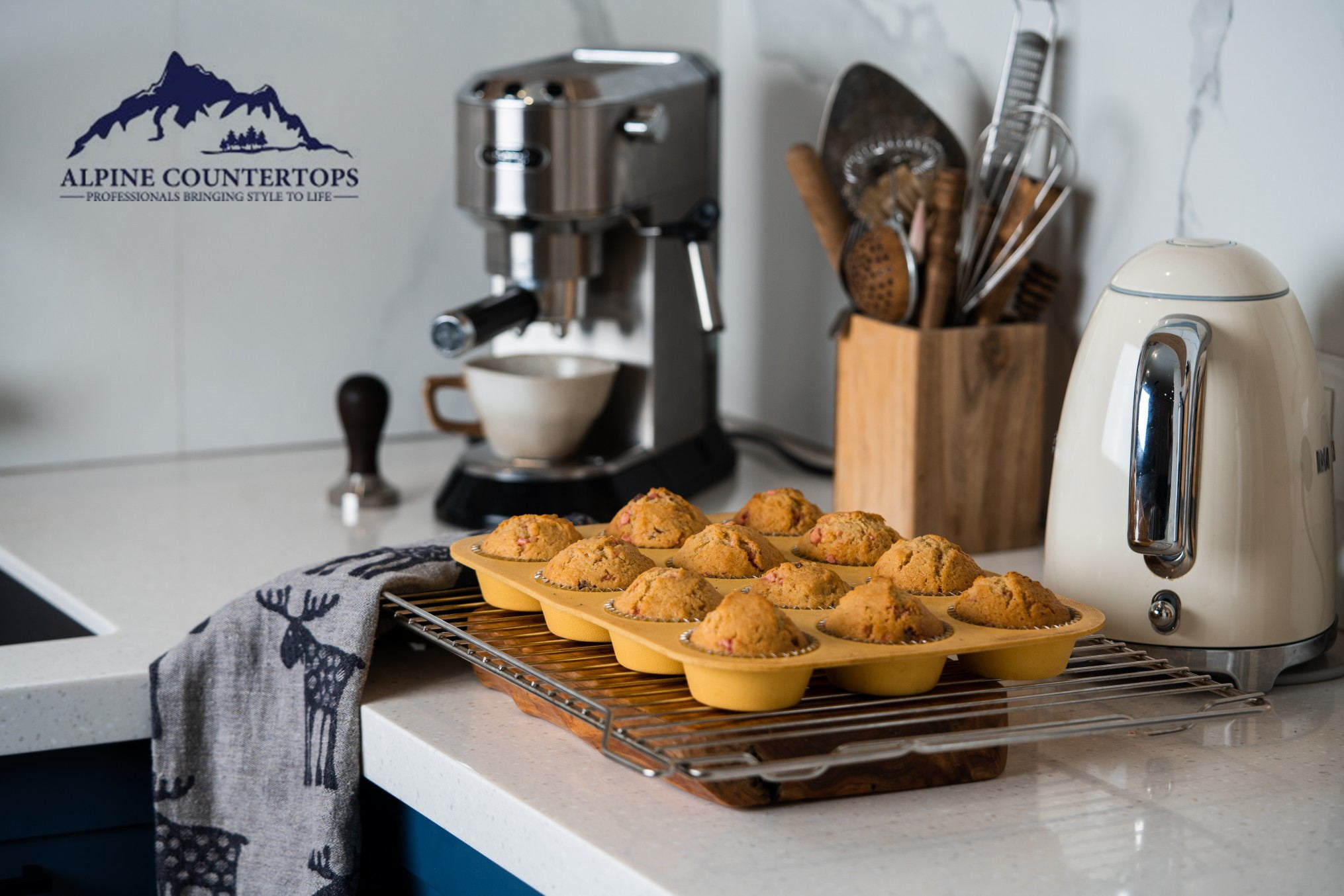 Muffins and coffee equipment on a pale counter above blue cabinets