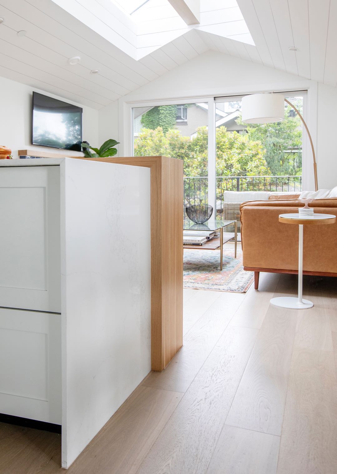 Waterfall countertop edge beside wood panelling and a sunlit room
